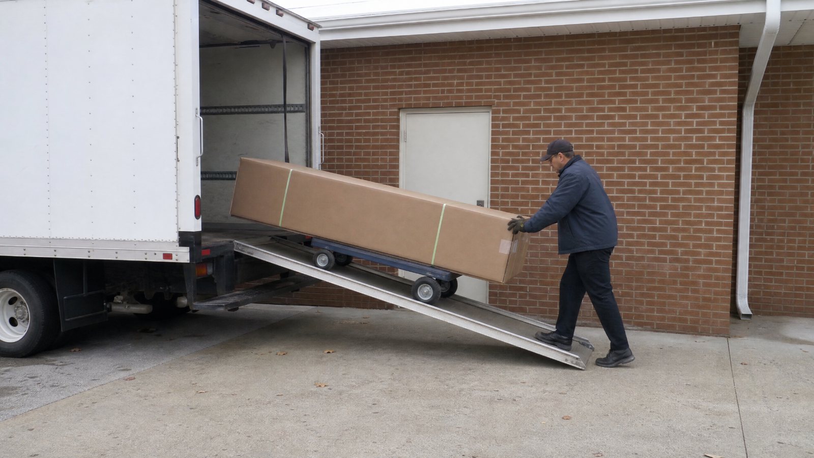 A plain steel casket in its shipping carton on a dolly
